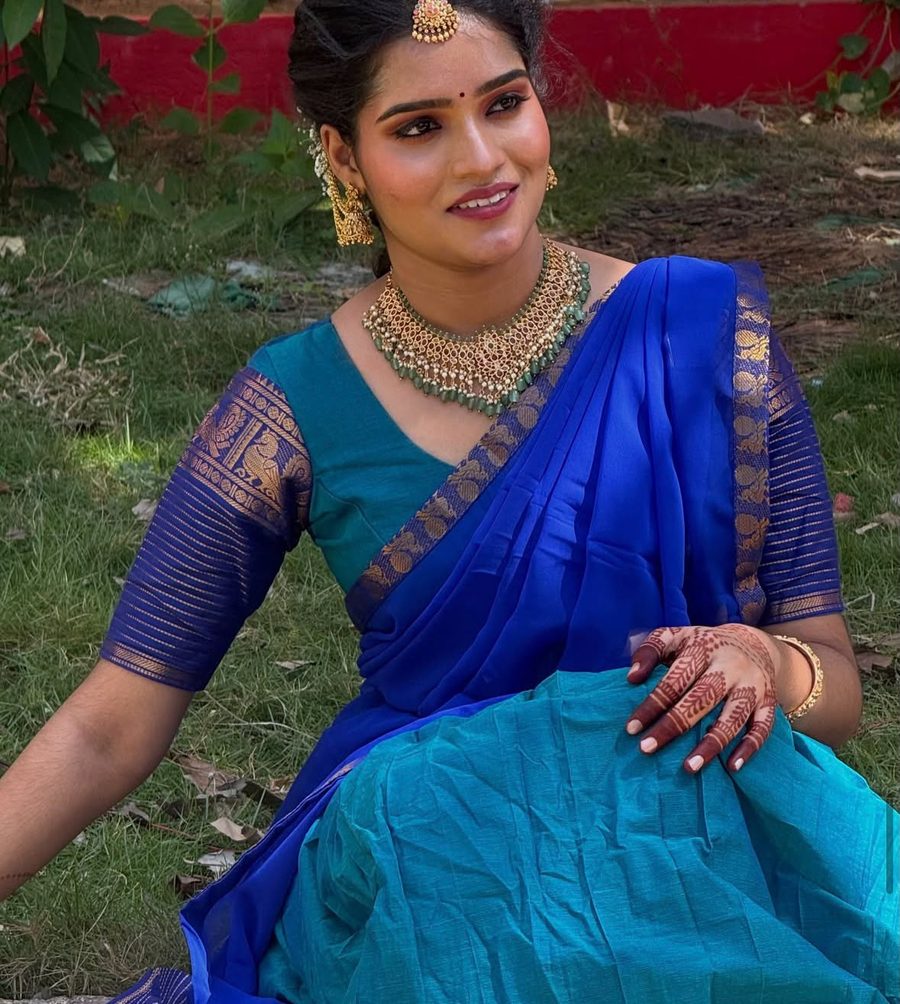 Bride in blue and teal silk saree seated outdoors